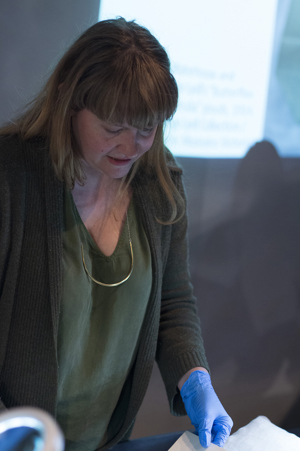 A woman wearing gloves handles a museum object.
