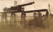 Trestle bridge under construction on the Warragul to Noojee line, post-1910. A travelling crane is sitting on the bridge and appears to be lowering a girder into position.
