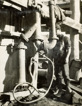 A man stands beside the hydraulic ejector pump which was used for draining water from the coffer dam during construction of the Mitchell River Bridge on the Bairnsdale to Orbost line, circa 1914.