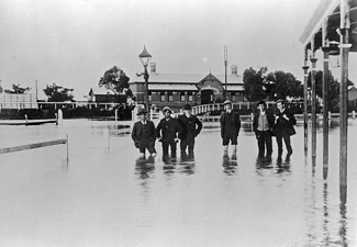 Men standing in floodwaters near the Railway Hotel and Warracknabeal Station, 23 August 1909