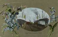 Rail trucks and two large ships berthed at Railway Pier (Station Pier), Port Melbourne, pre-December 1907. This is a greeting card with sprays of flowers on either side of the image.