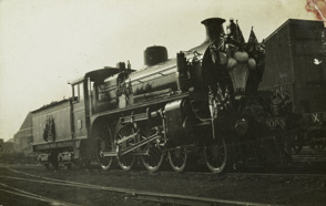 Steam engine used for the Prince of Wales' visit, 29 May 1920, decorated with flags including the Union Jack and Australian standards. The front of the engine carries a depiction of the Prince of Wales' emblem of three plumes.