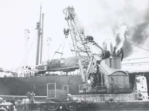 Steam crane at North Wharf, West Melbourne, unloading L class mainline electric locomotives built for the Victorian Railways by General Electric Co Ltd., Preston, England, from a ship, circa 1952