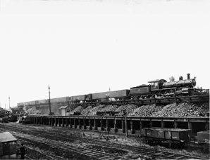 V class steam locomotive with 2-8-0 wheel arrangement and Oo class coal wagons, North Melbourne, circa 1900