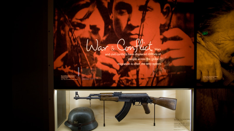 Leaving Home exhibition in Immigration Museum showing Motivations wall - War & Conflict 