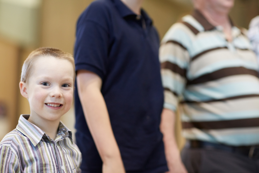 Boy smiling holding his dad's hand