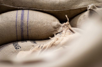 A close up of white hessian coffee bags with blue stripes. 