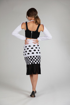 A girl is seen from the back modelling a long-sleeved black and white dress. It is detailed with complex cutouts and weaving to create circular and square patterns. 