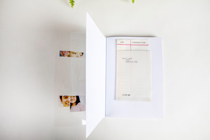A copy of a zine laying flat and opened on the first page. This includes a library-style loan slip with a piece of paper inside, stamped with a date in small black ink.