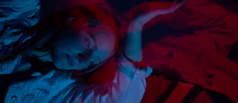 A girl is lying down, pensively staring into the distance with her hands above her head. A transparent image of the same girl in a similar pose is overlayed over the main image as if to demonstrate the passing of time 