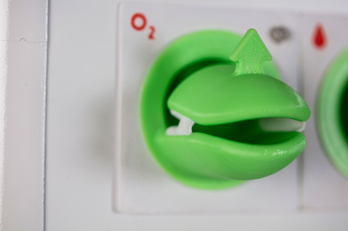 A close up of a green, plastic device the patient places their finger into to tests the patients oxygen levels. 