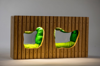 Close-up of a miniature model, two green cushioned enclaves in a wooden wall