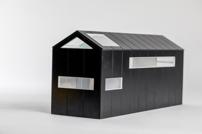 External three-quarter view of a compact, black painted modern house