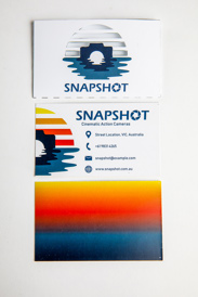 A business card case with a camera and water reflection logo, a business card with contact details, and the reverse side with a gradient of sunset colours