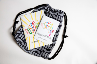 Two colourful books titled 'Australia Alive' sit closed on top of a black and white patterned backpack