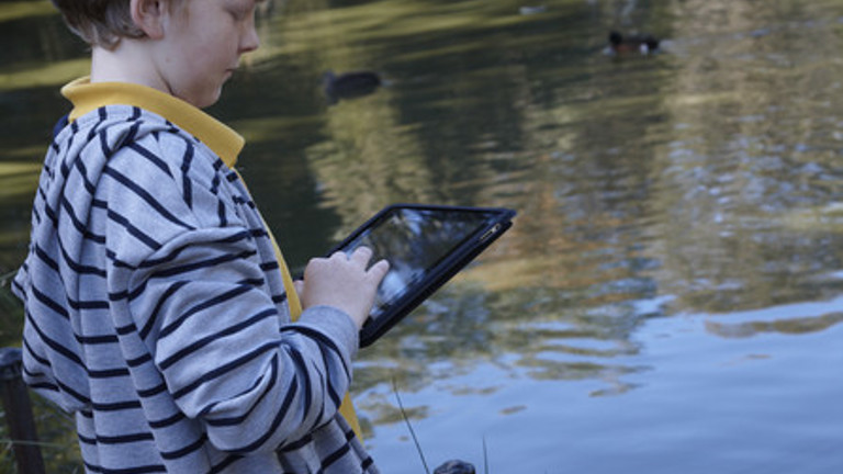 Child recording bird sightings on pad