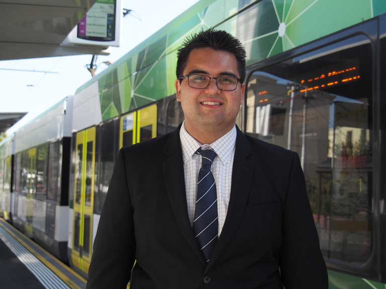 Matthew Weston, standing in front of a Melbourne tram