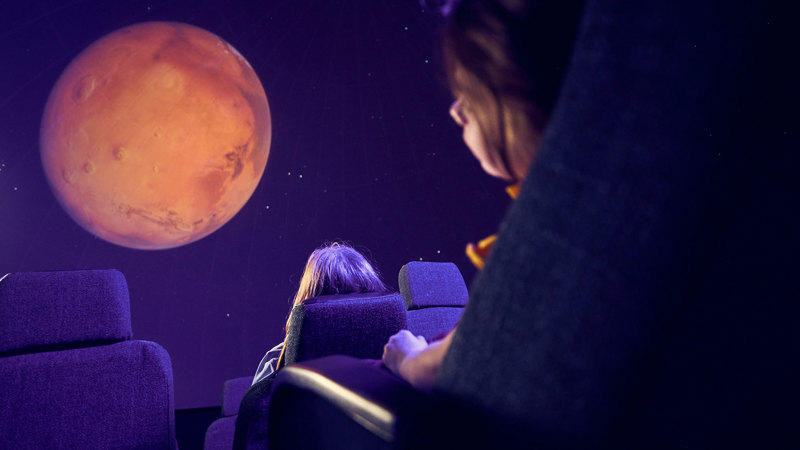 Primary and secondary school students observe a projection of Mars on the dome of the Melbourne Planetarium 