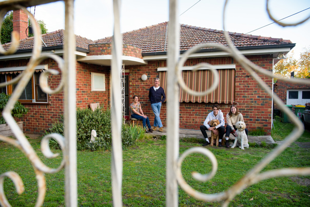 Family group next to house behind a fence