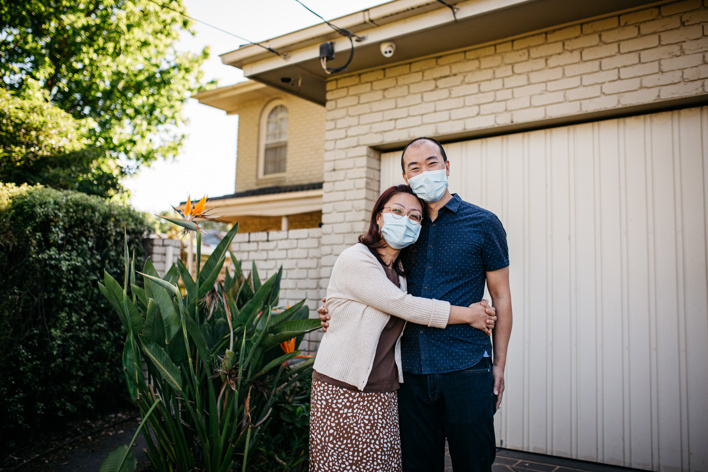Woman and a man embracing outside their suburban home