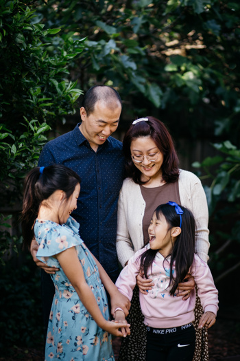 Family of four smiling at each other posing in their garden