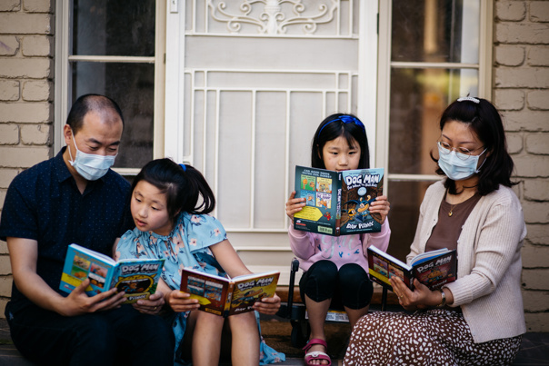 Family sitting on the front porch reading