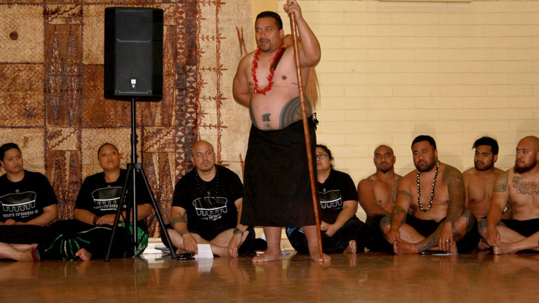 Man standing addressing a group of people sitting on the floor