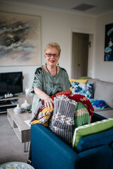 Woman standing with a pile of knitted garments