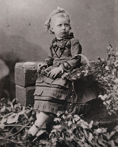 a black and white photo of a young child wearing a dress