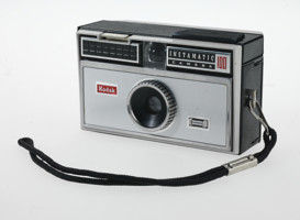 Small rectangular box camera. It is black and silver.