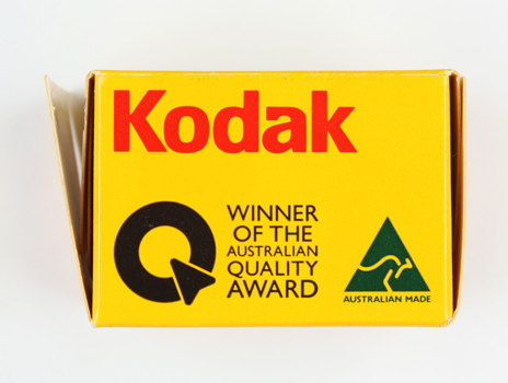 Side of an empty yellow cardboard box; opened; printed in black, gold and red colour scheme.