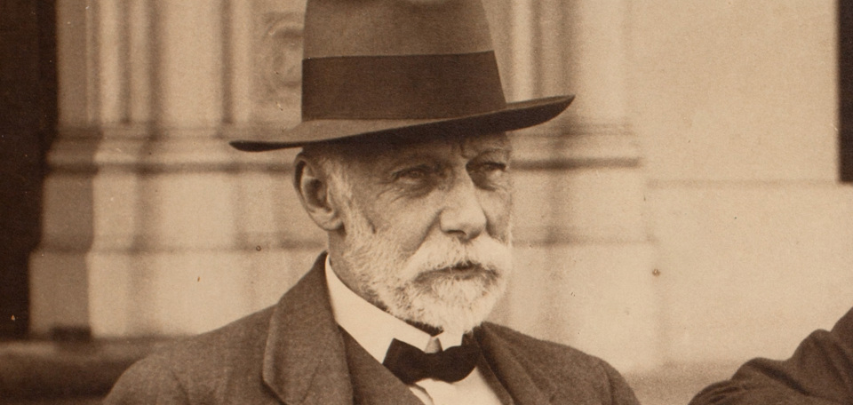 A bearded man in a hat and bow tie