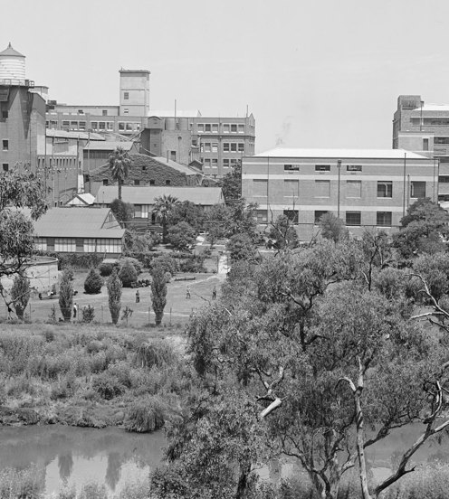 A view of factory buildings on the bank of a river from the opposite side