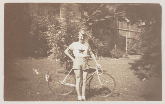 Young man in shorts leaning on bicycle