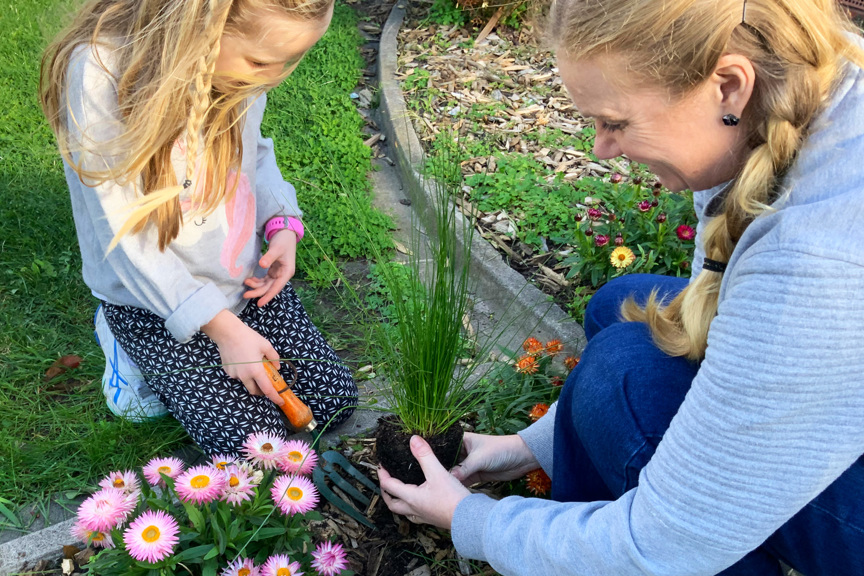 Woman and child planting a grass in a garden