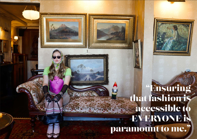 A girl sits on a chaise lounge, wearing sunglasses, a scarf, and long black gloves. Behind her hang several paintings of landscapes. A large quote overlaid on the image reads “ensuring that fashion is accessible to everyone is paramount to me”.
