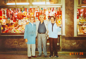 Three men pose in front of a butcher shop