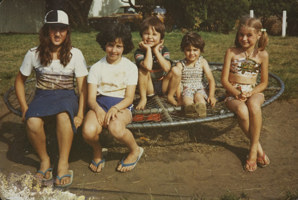 A group of children sit on a piece of playground equipment