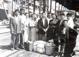 People of various ages standing on dock with suitcases.