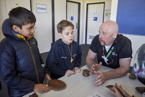 Children and a Museums Victoria staff member touching museum objects on a table