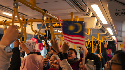 People waving Malaysian flags on a tram