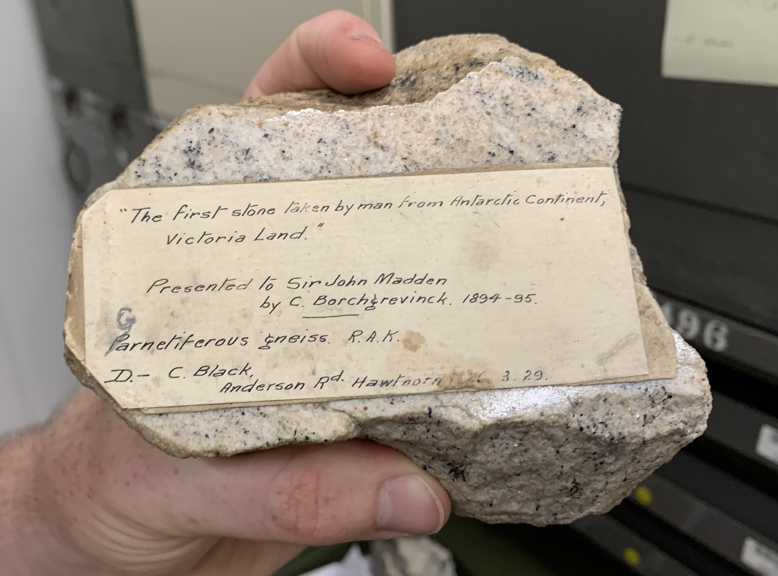 a hand holds a rock with a label 