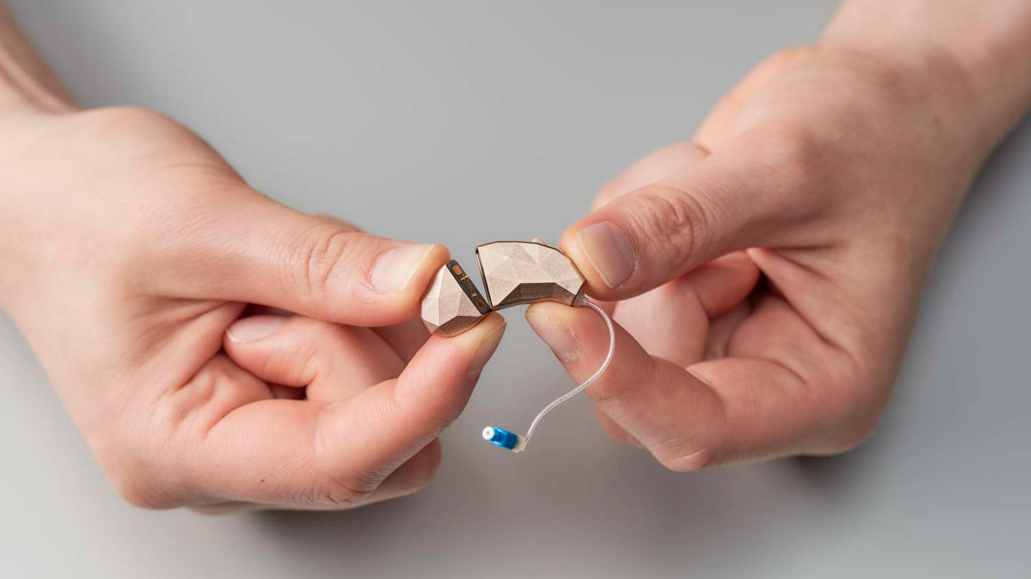 A small facetted object being held between the index finger and thumb of both hands