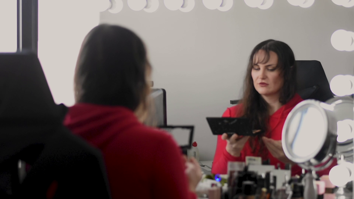 A woman putting on make-up in the mirror.