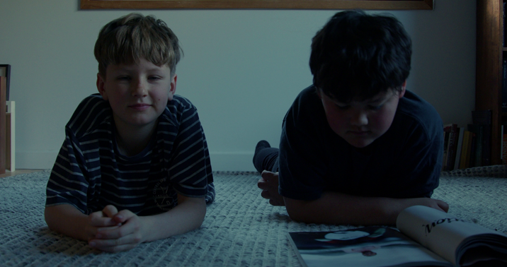 Two young boys lying on their front with a magazine in front of them.