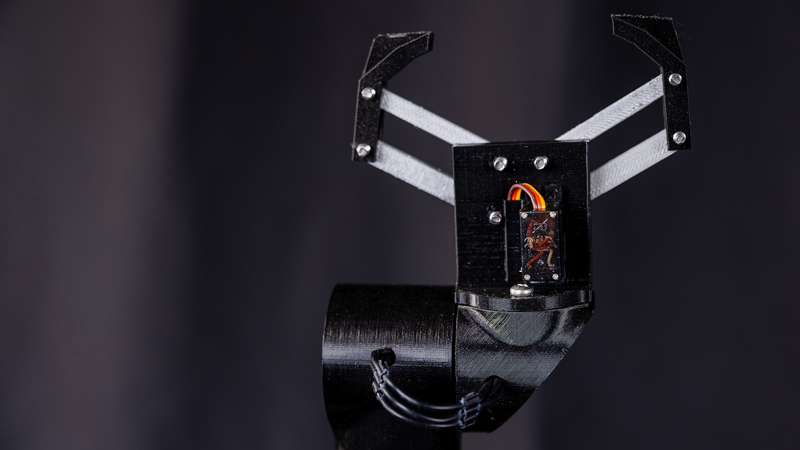 A black robotic arm with two claw like grips protruding at the top.