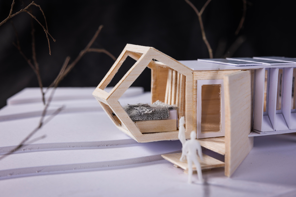 A close-up photo of an architectural model made of plywood and cardboard, with a  geometric structure. 
