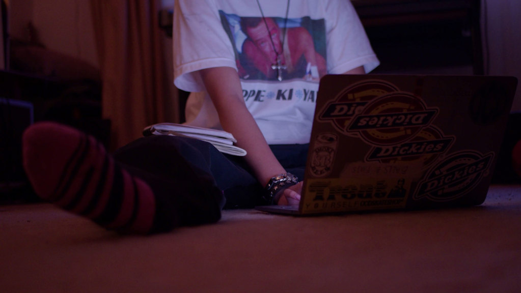 Someone sitting on the floor looking at a laptop. There head and face are not in shot