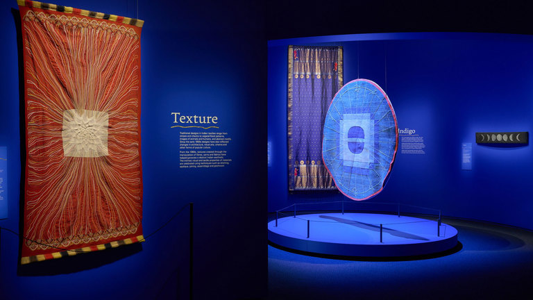 Blue exhibition space with textiles hanging on the wall