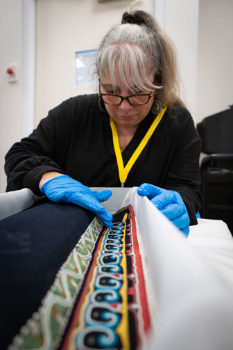 a woman touching a beaded cloth 